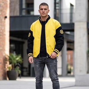 Puede incluir: Una chaqueta tipo bomber amarilla y negra con cuello alto, cremallera frontal completa y mangas negras con puños de rayas amarillas. La chaqueta muestra un emblema circular amarillo y negro con el logotipo de X-Men en cada manga.