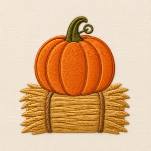 May include: An embroidery design featuring a bright orange pumpkin with a dark green stem resting on top of a rectangular bale of golden yellow hay, secured by two vertical brown twine ropes, all stitched onto a light cream fabric background.
