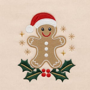 Puede incluir: Diseño navideño bordado con un hombre de jengibre con un gorro de Papá Noel. El hombre de jengibre tiene una cara sonriente y está rodeado de copos de nieve y acebo con bayas rojas. El diseño está sobre un fondo beige claro.