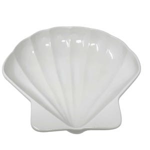 May include: A white, seashell-shaped serving dish. The dish has a scalloped edge and a smooth, glossy finish. The dish is designed to resemble a clam shell.