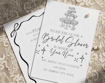 May include: Two white bridal shower invitations with black text and illustrations. One invitation features a champagne tower illustration, while the other has a decorative black border. The invitations include details for the event.