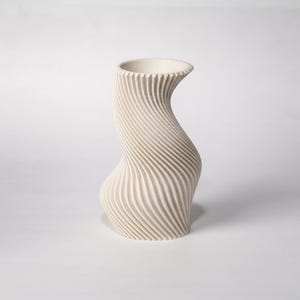 Peut inclure: Un vase sculptural de couleur crème avec un design torsadé unique. Le vase présente une surface texturée et nervurée qui s'enroule de la base à l'ouverture. La forme élégante et moderne convient à la décoration intérieure.