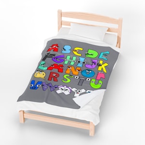 May include: A gray blanket with the alphabet letters A through Z, each letter is a different color and has a cartoon face. The blanket is on a small wooden bed with a white pillow.