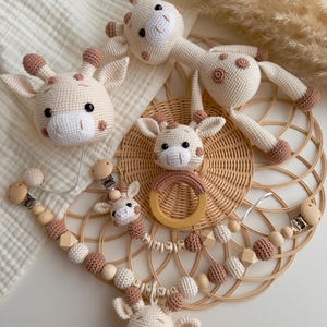 Puede incluir: Colección de juguetes y accesorios de jirafa de ganchillo hechos a mano en crema y marrón. Incluye una cabeza de jirafa, un sonajero de jirafa, un clip para chupete y un mordedor con forma de jirafa. Los accesorios están hechos con cuentas de madera y un anillo de madera.