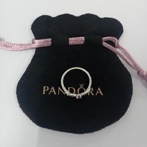 May include: A silver ring with a small purple gemstone, resting on a black velvet pouch. The pouch has a drawstring closure and the brand name "PANDORA" is printed on it. The ring is delicate and elegant.