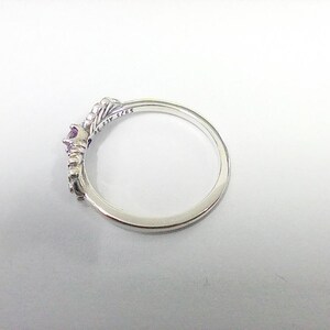 May include: A silver ring with a crown design, featuring a central purple gemstone and smaller accent stones. The ring is marked with "S925 ALE 56". The ring is set against a white background.