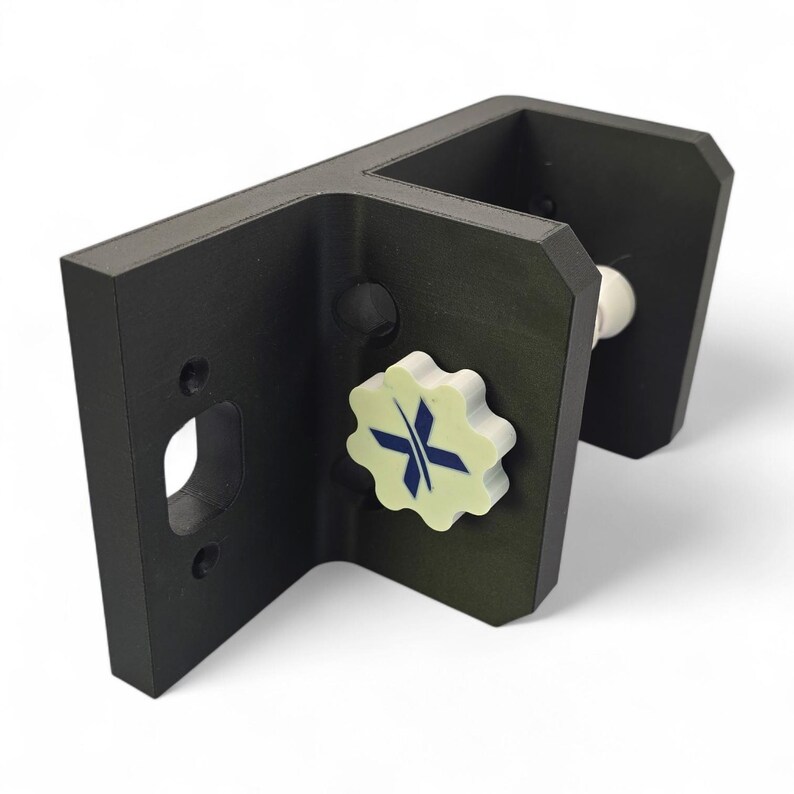 Pu&ograve; includere: Una staffa nera ad angolo retto con una manopola bianca a forma di stella con un design a croce blu. La staffa ha un'apertura rettangolare e un componente bianco a forma di sfera. L'oggetto &egrave; posto su uno sfondo bianco.