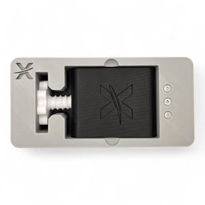 Peut inclure: Un cadre de bo&icirc;tier gris rectangulaire contenant un bloc central noir avec un logo X en relief. Un bouton de r&eacute;glage filet&eacute; blanc est positionn&eacute; sur la gauche, et trois petites fixations m&eacute;talliques circulaires sont align&eacute;es sur la droite.