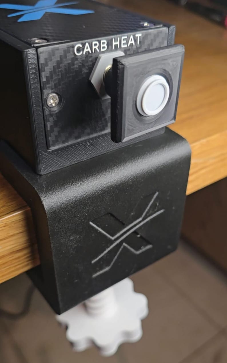 Peut inclure: Un bo&icirc;tier de commande noir &agrave; texture fibre de carbone, dot&eacute; d'un bouton blanc marqu&eacute; CARB HEAT et d'un logo X bleu sur le dessus. L'unit&eacute; est fix&eacute;e sur une base de serrage noire avec un logo X en relief et un bouton de serrage blanc en forme d'engrenage.