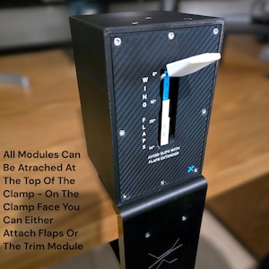 Pu&ograve; includere: Un modulo di controllo nero e argento con una leva bianca e segni blu. Il modulo ha il testo "WING", "FLAPS" e "AVOID SLIPS WITH FLAPS EXTENDED". Il testo aggiuntivo recita "All Modules Can Be Atrached At The Top Of The Clamp".