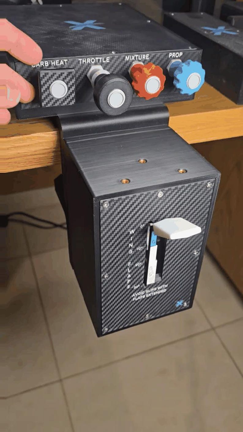 Peut inclure: Un bo&icirc;tier de commande de simulateur de vol noir avec une texture en fibre de carbone. Le panneau sup&eacute;rieur comporte des boutons &eacute;tiquet&eacute;s CARB HEAT, THROTTLE, MIXTURE et PROP. Le panneau avant vertical inclut un levier WING FLAPS gradu&eacute; de 0 &agrave; 30.