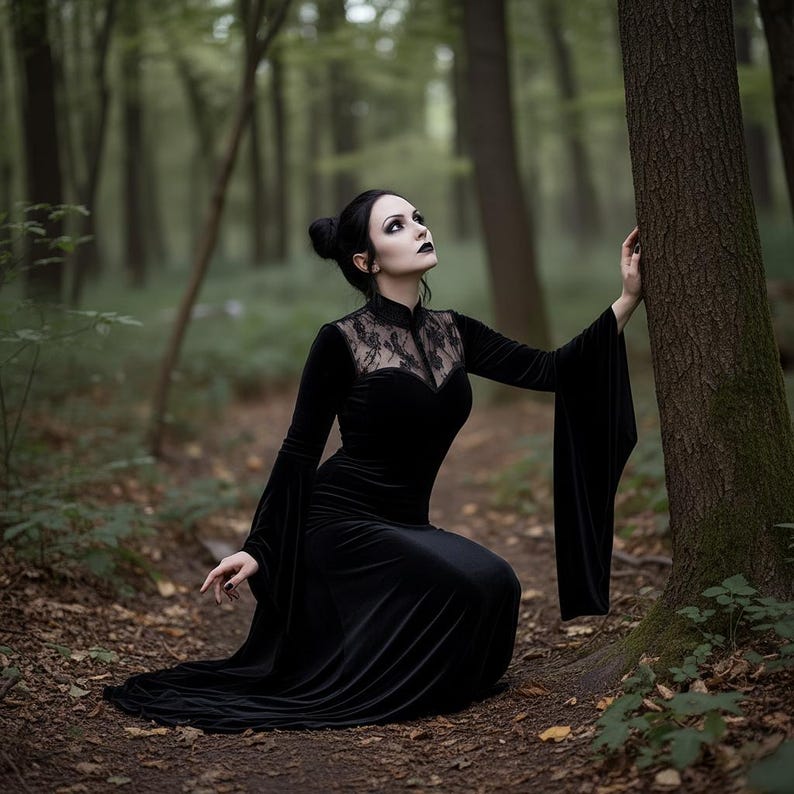May include: A black velvet gown with a high collar and lace detailing on the bodice. The dress features long, flowing sleeves and a floor-length skirt. The woman is kneeling in a forest setting, creating a gothic or dark aesthetic.