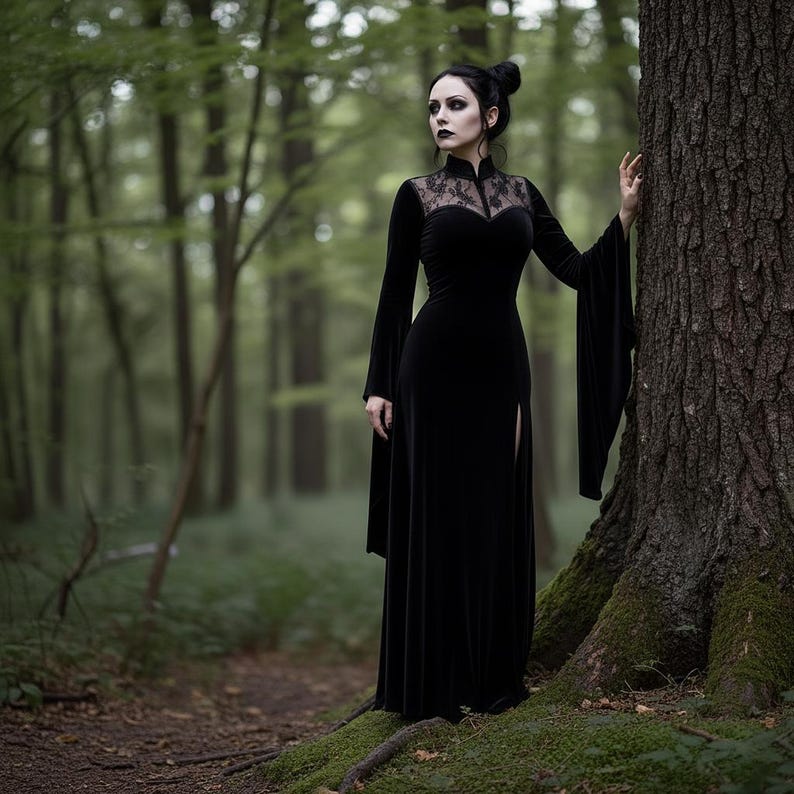 May include: A long, black velvet dress with a high collar and lace detailing. The dress features long sleeves with flared cuffs and a thigh-high slit. The woman in the dress is standing in a forest.
