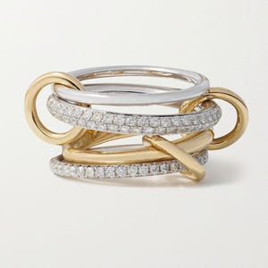 May include: A multi-band ring with a complex design. The ring features bands of gold and silver, some encrusted with small, sparkling stones. The bands are intertwined, creating a unique and eye-catching piece of jewelry.
