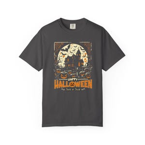 May include: A charcoal gray short-sleeve t-shirt featuring a graphic print of a haunted house, bats, and jack-o'-lanterns against a full moon. The text reads Happy Halloween and Trick or Treat in orange and white lettering.