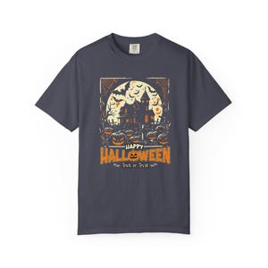 May include: A charcoal gray short-sleeve t-shirt featuring a graphic of a haunted house, bats, and jack-o'-lanterns in front of a full moon. The text reads Happy Halloween and Trick or Treat in orange and white lettering.