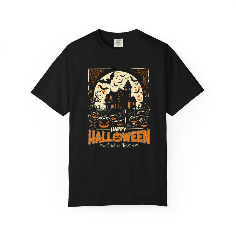 May include: A black short-sleeve t-shirt featuring a graphic print of a haunted house, a full moon, bats, and jack-o'-lanterns. The text reads Happy Halloween and Trick or Treat in orange and white lettering centered on the chest.