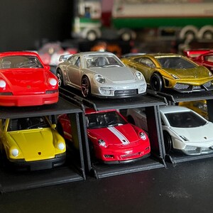 May include: A collection of miniature toy cars in various colors, including yellow, red, silver, and gold. The cars are displayed on black tiered shelves, showcasing different models and designs. The collection includes sports cars and classic car models.