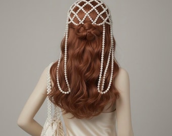 May include: A mannequin is shown from the back, wearing a cream-colored satin dress. The mannequin's auburn hair is styled with a pearl headpiece and long pearl strands. A small, white, pearl-covered bag hangs from the mannequin's arm.