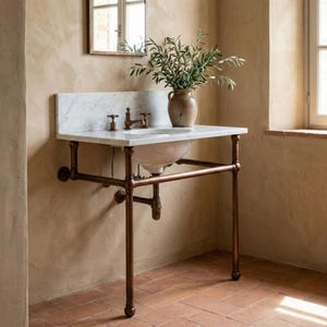 May include: A vintage-style bathroom sink with a white marble countertop and a copper pipe frame. The sink has a white basin and copper fixtures. A vase with green branches sits on the countertop. The sink is mounted on a brick-tiled floor.