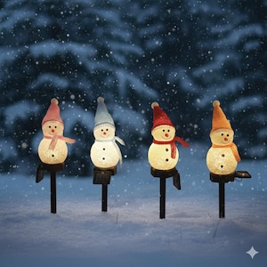 Peut inclure: Quatre piquets de jardin en forme de bonhomme de neige illuminés avec des poteaux noirs. Chaque bonhomme de neige a un chapeau et une écharpe de couleur différente : rose, bleu, rouge et orange. Les bonhommes de neige sont éclairés, avec un fond enneigé.