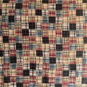 Puede incluir: Una colcha de retazos con una cuadrícula repetitiva de parches de tela cuadrados. El diseño consiste en varios patrones de cuadros y tartán en una paleta de colores rojo oscuro, azul marino, verde bosque, crema y negro, en una disposición uniforme.