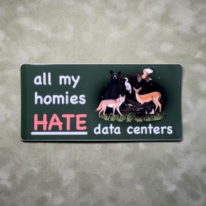 Op de afbeelding: Een rechthoekige sticker met een donkergroene achtergrond en de witte en roze tekst "all my homies HATE data centers". Het ontwerp bevat illustraties van een zwarte beer, een coyote, een hert, een stinkdier, een witte vogel en een havik.