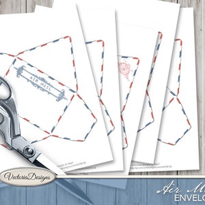 May include: A set of printable paper templates for air mail envelopes featuring a classic red and blue striped border design. One template displays the text AIR MAIL in a decorative frame. A pair of silver metal scissors is positioned over the sheets.
