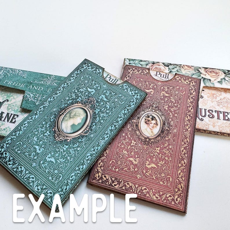 May include: Two rectangular paper card holders with pull tabs, one in teal and one in maroon, both featuring intricate filigree patterns, ornate oval frames containing portraits of women, and the word Pull printed on the top tab of each item.