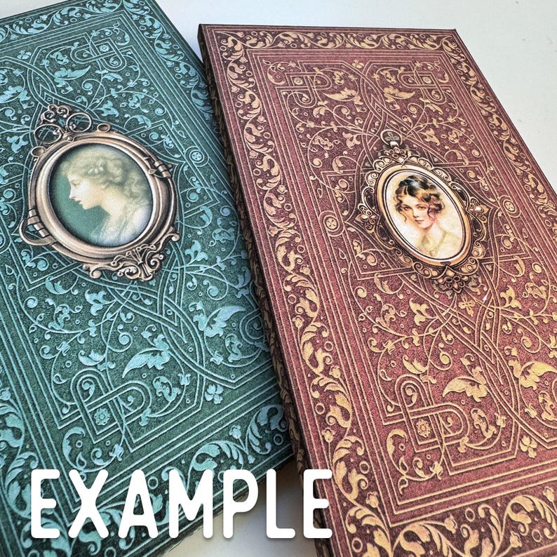 May include: Two rectangular books with ornate, embossed floral patterns. One book is teal with a silver-toned oval cameo featuring a woman's profile. The other book is deep red with a gold-toned oval cameo featuring a woman's portrait.