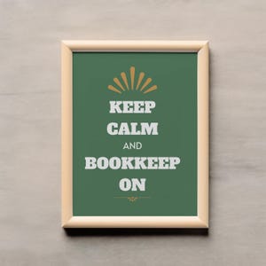 May include: A framed print with the words "KEEP CALM AND BOOKKEEP ON" in white block letters on a green background. The print has a light brown frame and a decorative orange sunburst design at the top.