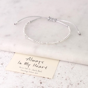 Puede incluir: Una taza de cerámica blanca con un asa negra y el texto "But First, Coffee" en negro, con una fuente de estilo manuscrito. La taza está sobre una superficie blanca.