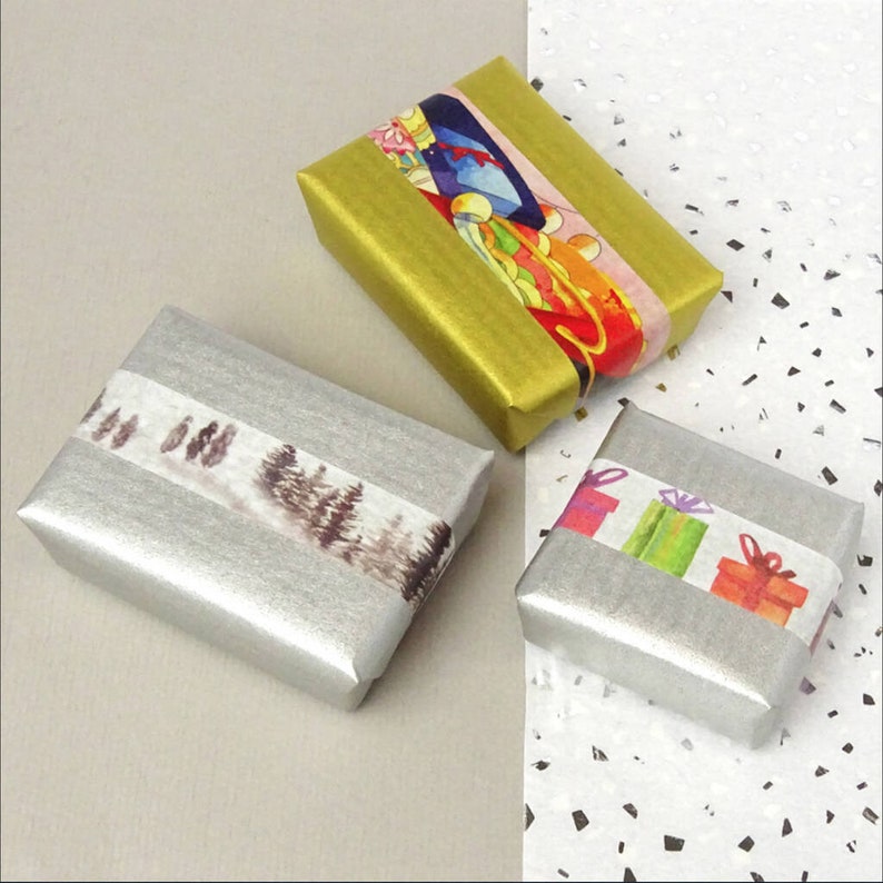 K&ouml;nnte beinhalten: Drei verpackte Geschenke mit dekorativem Washi-Tape. Eines ist goldfarben mit einem bunten Design, und zwei sind silberfarben mit Wald- und Geschenkbox-Mustern. Die Geschenke sind auf einem zweifarbigen Hintergrund angeordnet.