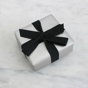 May include: A silver gift box with a black ribbon tied in a bow.