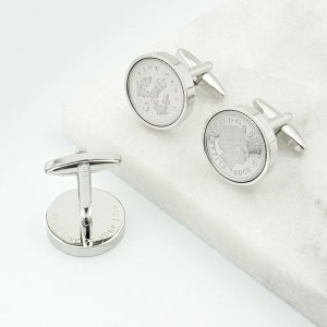 May include: Silver cufflinks featuring a five pence coin with the inscription "Five Pence" and a portrait of Queen Elizabeth II. The back of the cufflinks are engraved with the text "I fall love with your smile".