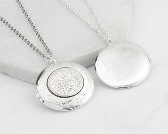 May include: Two silver-colored round lockets on delicate chains. One locket features a coin design, while the other has engraved text. The lockets are displayed on a white surface.