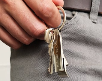 May include: A silver bottle opener keychain with the inscription "Happy 40th Birthday!" attached to a set of keys.