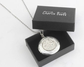 May include: A silver locket necklace with an ornate design, in a black box with the words "Charlie Boots" printed on the top.