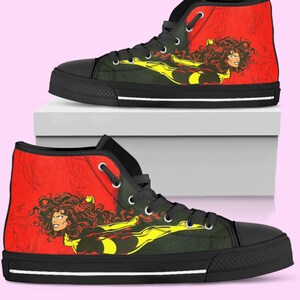 May include: Pair of high-top sneakers featuring a comic book-style illustration. The design includes a woman with flowing hair in a red and yellow color scheme against a red background. The shoes have black soles, laces, and eyelets.