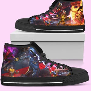 May include: High-top canvas sneakers with a black rubber sole and toe cap. The shoes feature a colorful graphic design of comic book characters in action, with a red and purple background. The laces are black.
