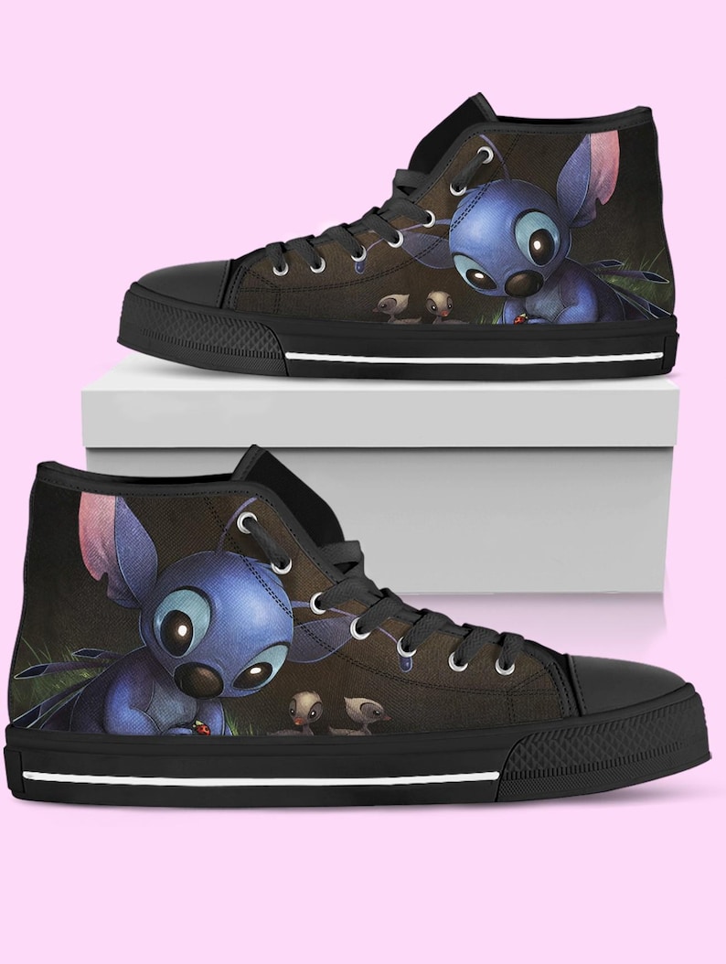 May include: High-top canvas sneakers featuring a blue cartoon character with large eyes and ears. The shoes have a black sole, laces, and toe cap. The background is dark with a hint of green.