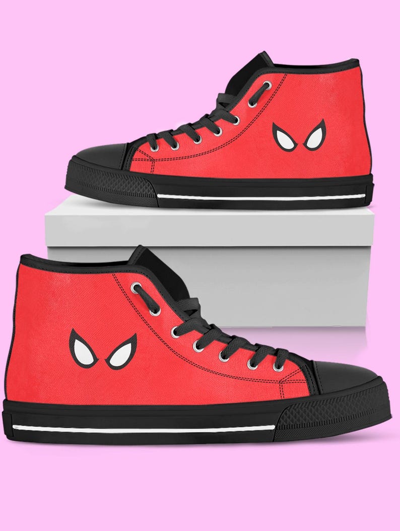 May include: Pair of red high-top sneakers with black accents. The sneakers feature a white eye-shaped design on the side and black laces. The soles are black with a white stripe.