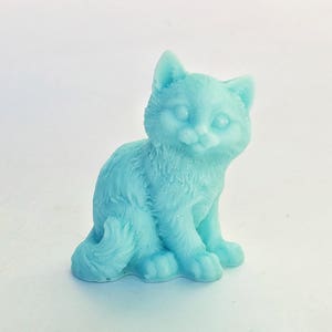 May include: A light blue ceramic figurine of a cat sitting with its paws tucked under its body. The cat has a sweet expression on its face.
