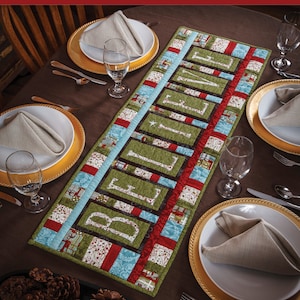 Könnte beinhalten: Ein gesteppter Tischläufer mit dem Wort "Believe" in grünen Stoffbuchstaben. Der Läufer ist aus verschiedenen Stoffen in Rot, Blau, Grün und Weiß gefertigt. Der Läufer ist auf einem braunen Tisch mit goldenen Untersetzern und weißen Tellern drapiert.
