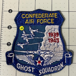 May include: A shield-shaped embroidered patch featuring the text CONFEDERATE AIR FORCE and GHOST SQUADRON in yellow and white. It depicts three white aircraft, a large plane, and the years 1939-1945 in red, set against a blue background.