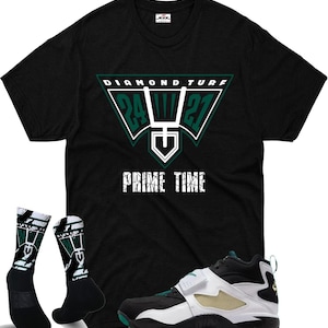 May include: Black t-shirt with a green and white graphic that reads "Diamond Turf" and "Prime Time". The image also shows black and white socks with a green design, and black, white, and green athletic shoes.