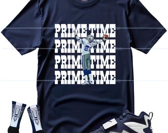 May include: Navy blue t-shirt with a graphic of a football player and the text "PRIME TIME" repeated. The image also includes a pair of socks with a geometric design and navy blue and white sneakers.