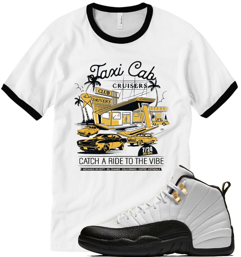 May include: White t-shirt with black trim featuring a yellow and black graphic of a retro taxi cab service. The graphic includes the text "Taxi Cab Cruisers" and "Catch a Ride to the Vibe". A white and black sneaker is in the foreground.
