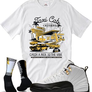 May include: A white t-shirt with a Taxi Cab Cruisers graphic, black and white checkered socks, and white and black sneakers. The shirt features a retro design with cars and the text "Catch a Ride to the Vibe."