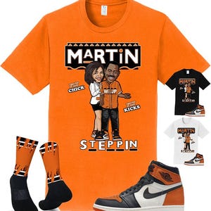 May include: Orange t-shirt with a cartoon graphic of a couple and the word "MARTIN" above them. The shirt also features the word "STEPPIN" and the phrases "FLY CHICK" and "FLY KICKS". The image includes matching socks and a pair of orange and black sneakers.